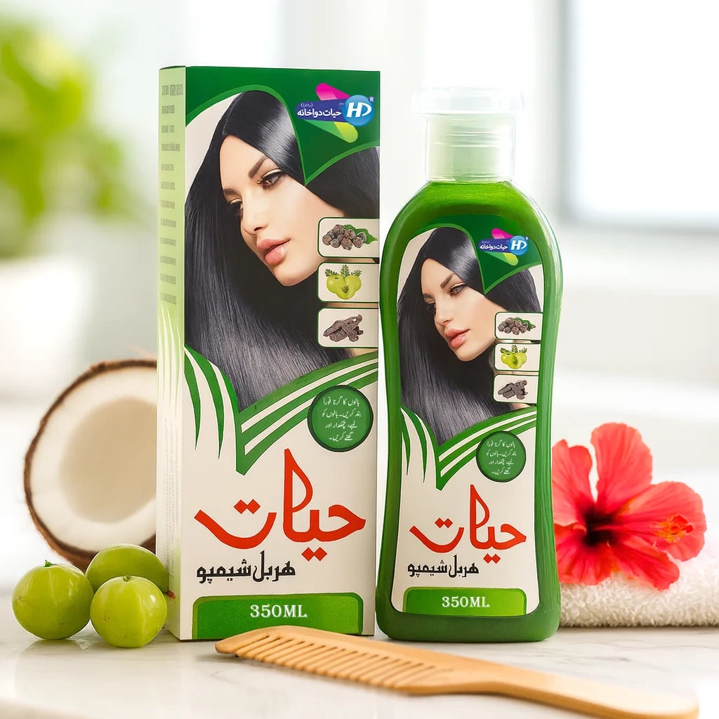 Hayat Herbal Shampoo 350ml bottle and packaging displayed with coconut, amla fruits, hibiscus flower, and wooden comb in a bright setting.