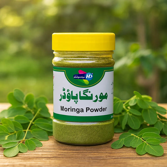 Hayat Dawakhana Moringa Powder jar shown with fresh moringa leaves in a natural green outdoor wellness background.