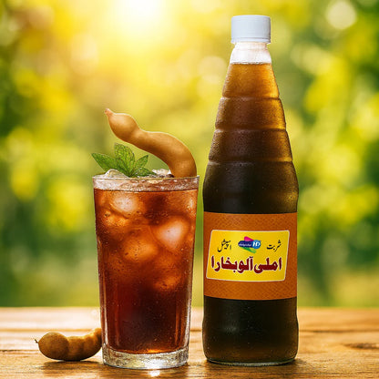 Sharbat Imli Alu Bukhara bottle with a chilled tamarind drink and fresh tamarind pods on a wooden table in a bright outdoor setting.