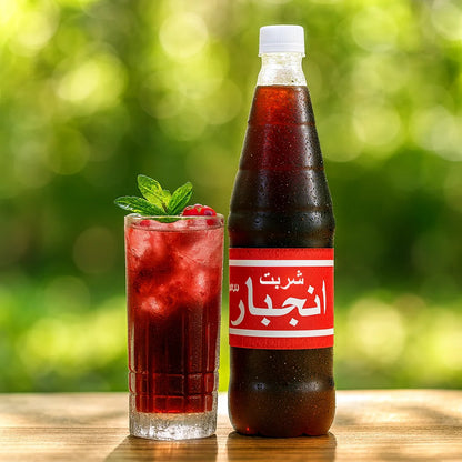 Sharbat Anjbar bottle beside a chilled red herbal drink with mint and berries on a wooden table in natural sunlight.